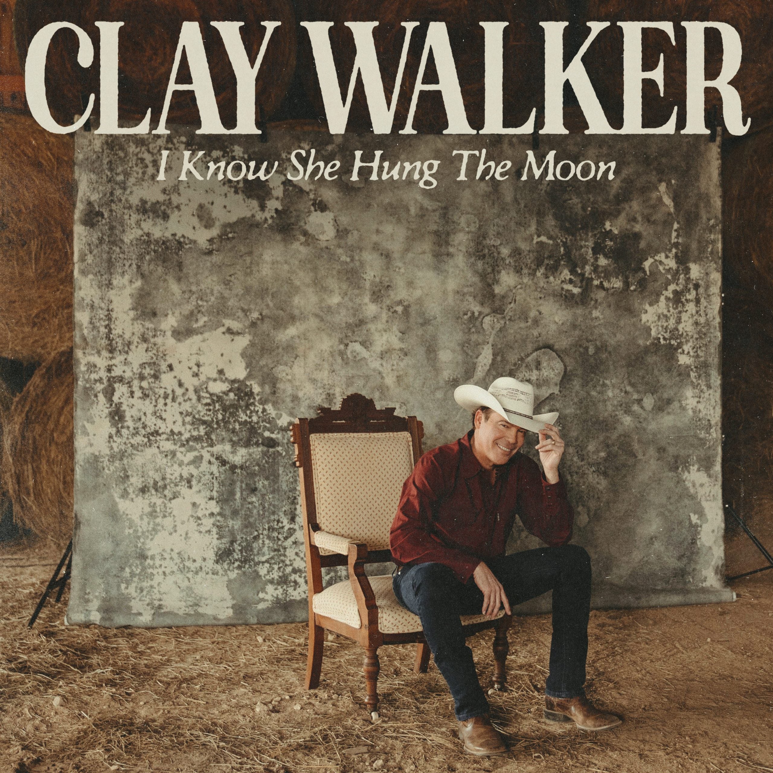 Album cover with a person sitting on a chair, wearing a cowboy hat, against a textured wall with 'Clay Walker' and song title text.